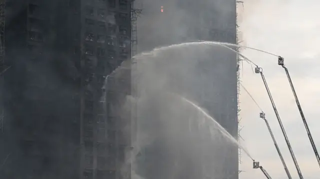 Firefighters spray water on flames as a major fire burns through several apartment blocks at the Wang Fuk Court residential estate in Hong Kong's Tai Po district