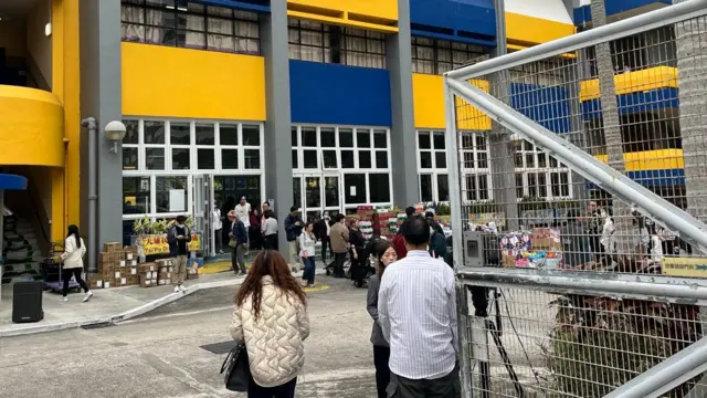 People filter in and out of a blue and yellow community centre in Hong Kong.