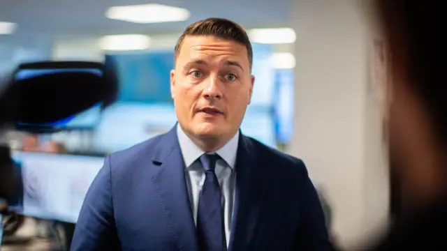 Wes Streeting speaks to a reporter wearing a blue suit