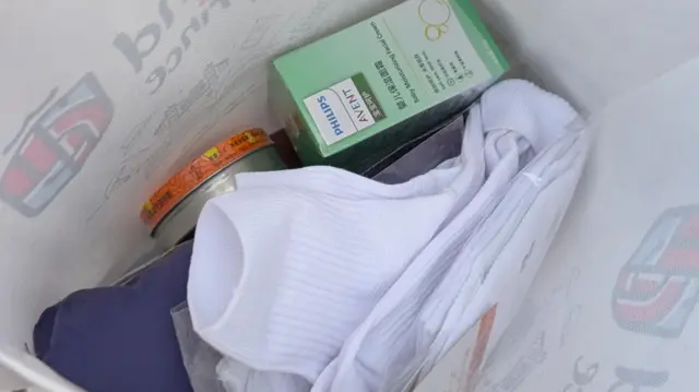 Inside a white plastic bag are pairs of white socks, a moisturising cream for babies and other supplies