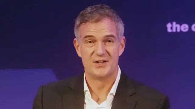 Business Secretary Peter Kyle who has grey-black hair and is wearing a dark suit and an open-necked white shirt