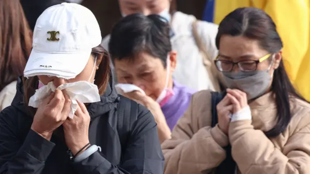 Relatives react after identifying a family member from photos at Kwong Fuk Community Hall following the Wang Fuk Court housing estate fire in Hong Kong.