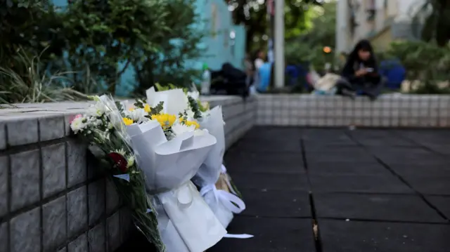 A close up shot of flowers and paper notes leaning against a short wall