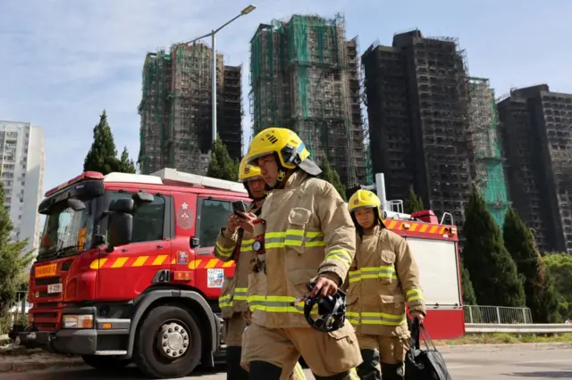 Firefighters walk near the site of a major fire at Wang Fuk Court housing complex, where flames engulfed bamboo scaffolding across multiple blocks, in Tai Po, Hong Kong, China, November 28, 2025.