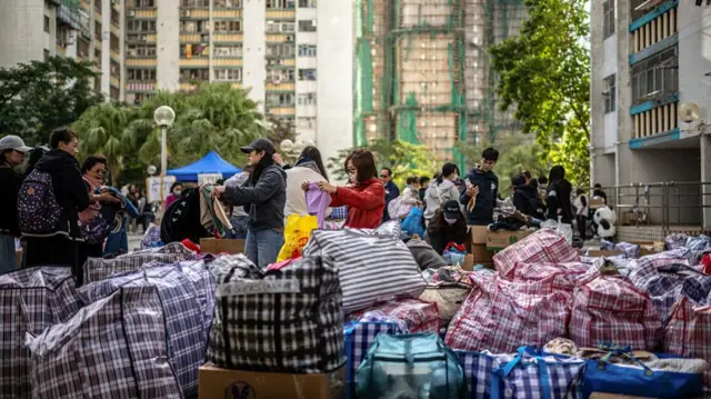 People sorting through large bags on the ground - relief supplies donated by others