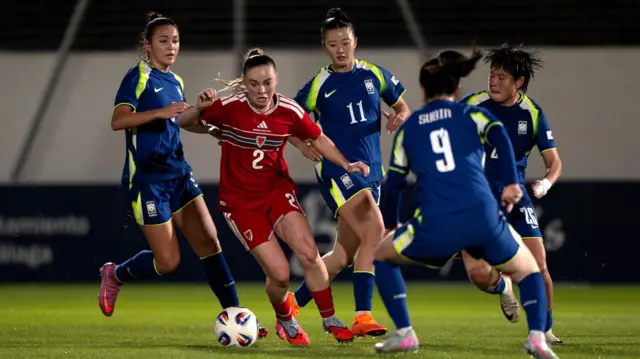 Lily Woodham carries the ball away from several South Korea players