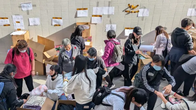 Volunteers sort through donations for those affected by the fire, the wall is covered with paper notes