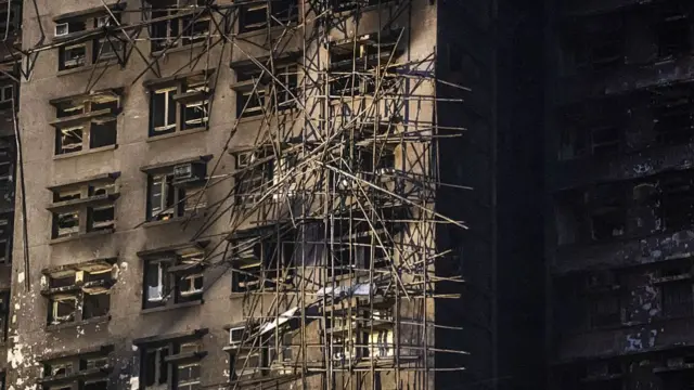 A charred building with tangled bamboo scaffolding outside of it
