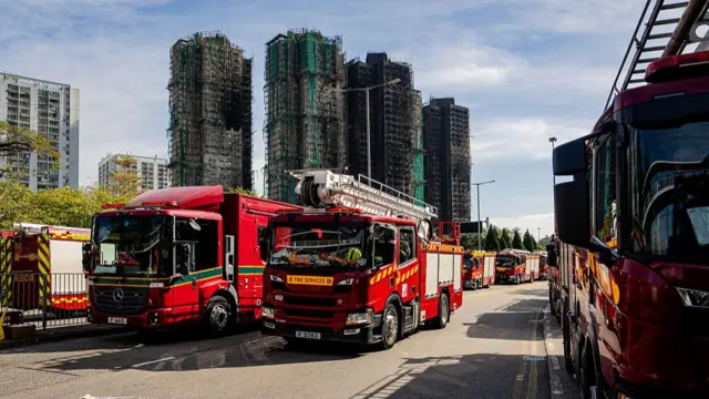 Several fire trucks are parked in front of the balackened buildings