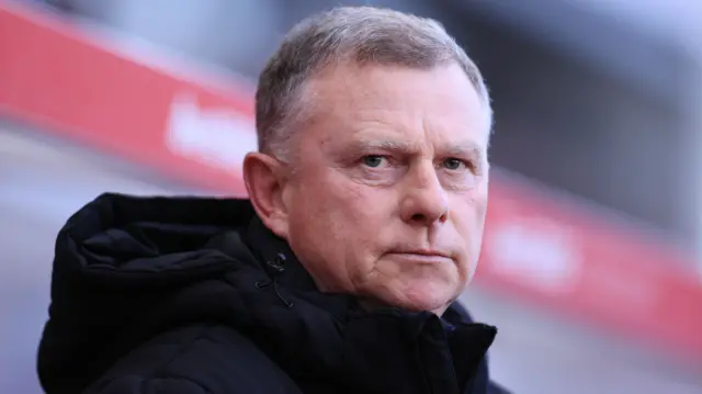 A headshot of Stoke City boss Mark Robins dressed in a big black puffer coat