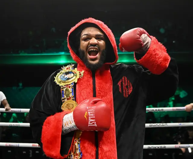 Jeamie TKV celebrates with the British heavyweight title over his shoulder