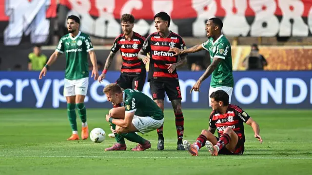 Bruno Fuchs of Palmeiras falls down after a foul from Erick Pulgar of Flamengo during the 2025 Copa CONMEBOL Libertadores Final match between Palmeiras and Flamengo at Estadio Monumental