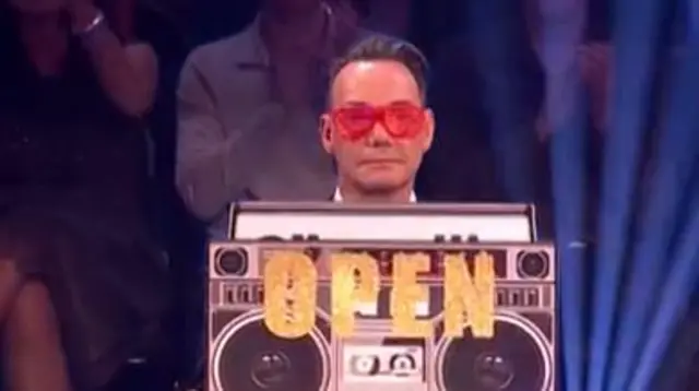 Craig holding a sign saying open on it