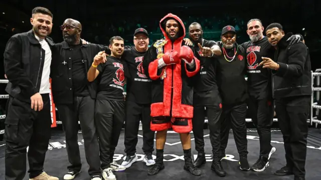Jeamie TKV celebrates with his team in a boxing ring