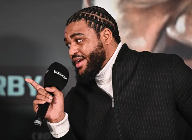 Jeamie 'TKV' Tshikeva holding a microphone and pointing