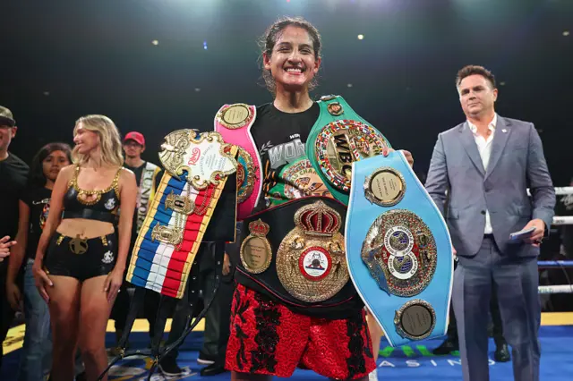 Gabriela Fundora holds the WBA, WBC, IBF, WBO & The Ring flyweight titles over her shoulders