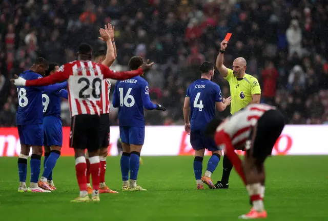 Match referee Tim Robinson shows a red card to Lewis Cook