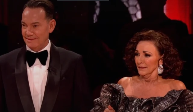 Shirley looks perplexed next to Craig as they watch the instant dance challenge