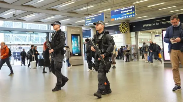 Two officers with guns walk along inside St Pancras station