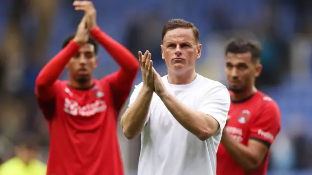 Leyton Orient manager Richie Wellens claps fans with two players standing behind him