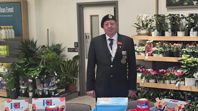 Andrew Johnson at British Royal Legion stand. He is wearing a suit and a poppy