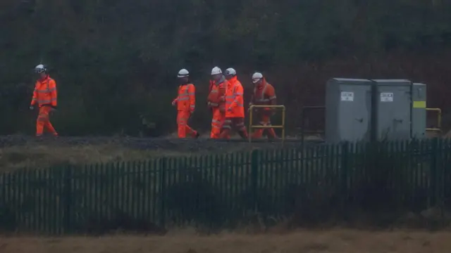 Rail workers walk along the track near the site of the derailment near Shap