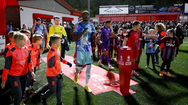 Tamworth and Leyton Orient players make their way onto the pitch at The Lamb Ground