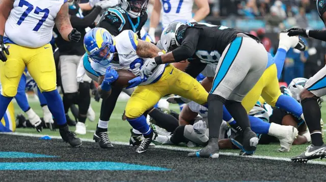 Blake Corum powers his way past Carolina Panther defenders and into the endzone.