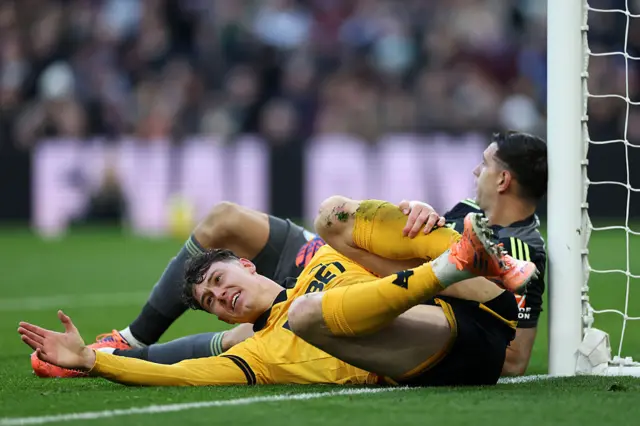 Jorgen Strand Larsen holds his leg after clashing with Emiliano Martinez