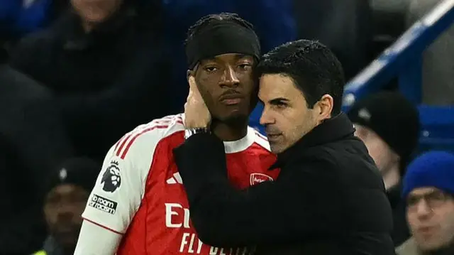 Mikel Arteta (R) speaks with Noni Madueke (L)