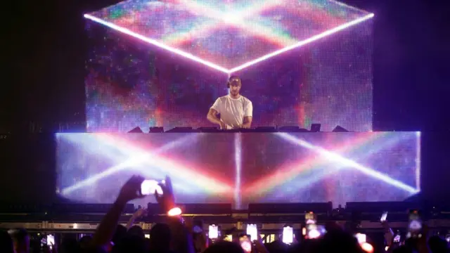 Calvin Harris performing live, several people below photograph him using mobile phones.