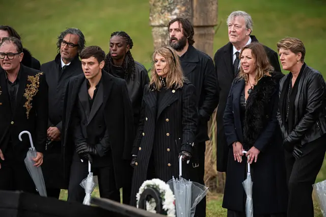 Alan, David, Cat, Tom, Kate, Stephen, Charlotte and Claire dressed in black looking at their fake graves
