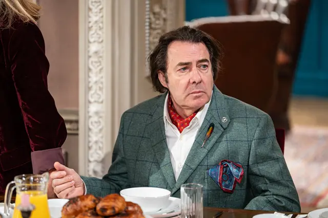 Ross in a teal blazer, with a neckerchief and hanky hanging from his front pocket