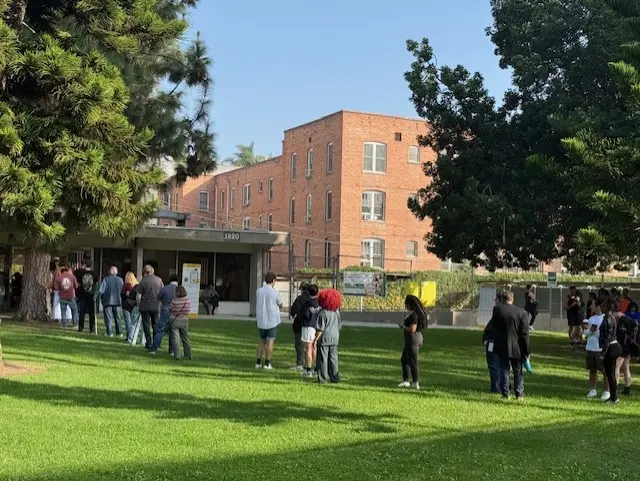 People line up to vote outside a brick building in California
