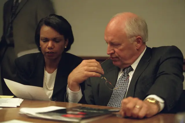 Former Secretary of State Condoleezza Rice and Dick Cheney sitting together in a conference room.