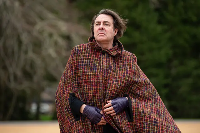 Jonathan Ross wearing a plaid cape and fingerless gloves