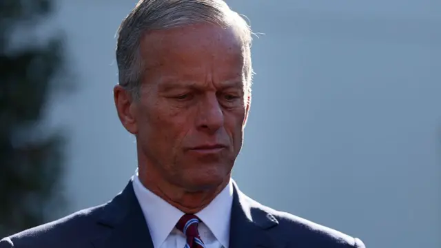 A photo of John Thorne wearing a suit. He is looking downwards with a serious expression on his face.