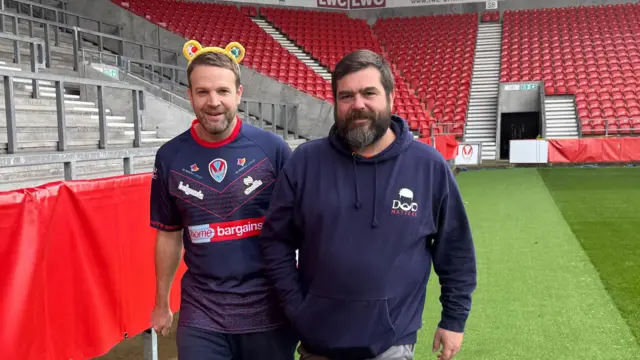 Paul Salt and a volunteer walk three-legged around a stadium