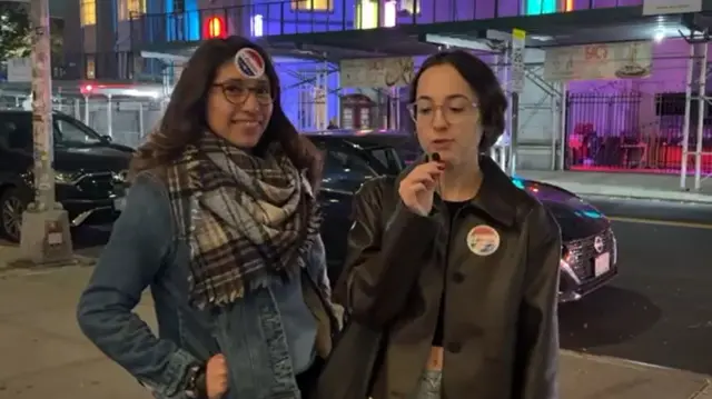 Two young women standing on a New York street sidewalk