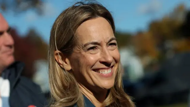 A blonde woman smiles broadly