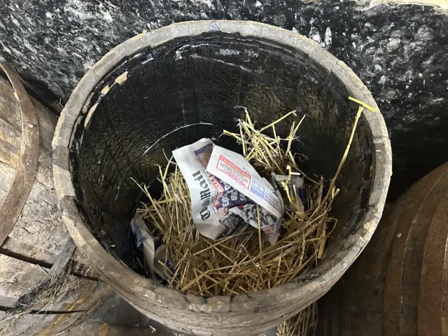 Inside a tar barrel which is lined with tar and has straw and paper inside of it.