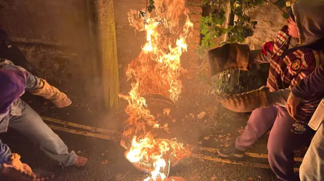 A flaming tar barrel lights up a plant.