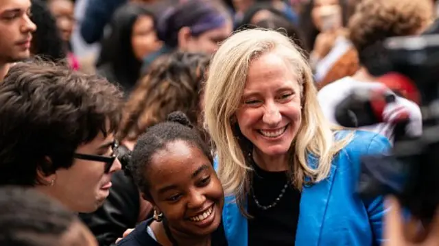Blond woman in blue jacket smiling in crowd