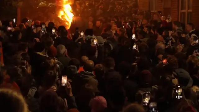 A flaming barrel amongst a large crowd of people