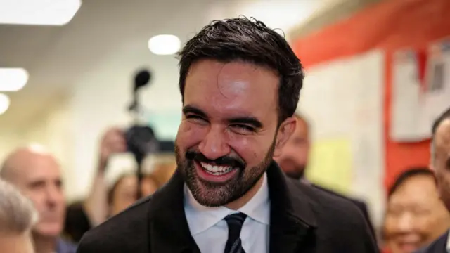 A man with dark hair smiles broadly