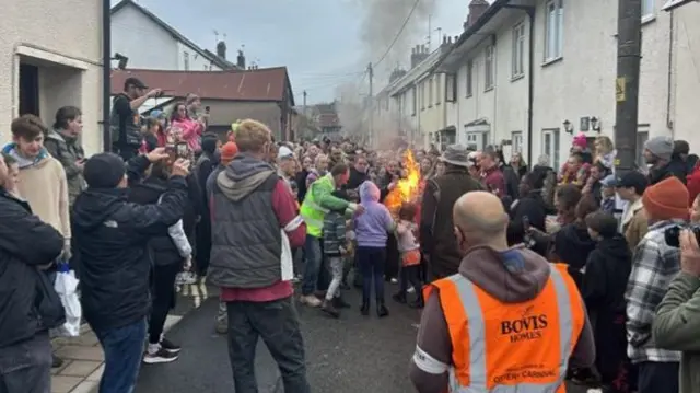 A crowd of people surrounding a flaming barrel