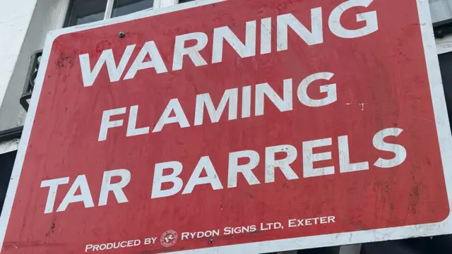 A sign warning people of flaming tar barrels. It reads "Warning flaming tar barrels"