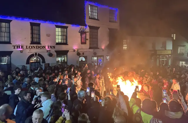 Crowds gather outside a white building.