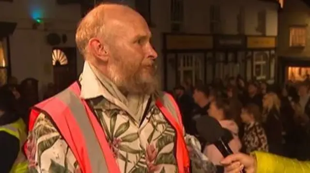 Darrin Abbott is wearing a Hawaiian shirt with a vest on.