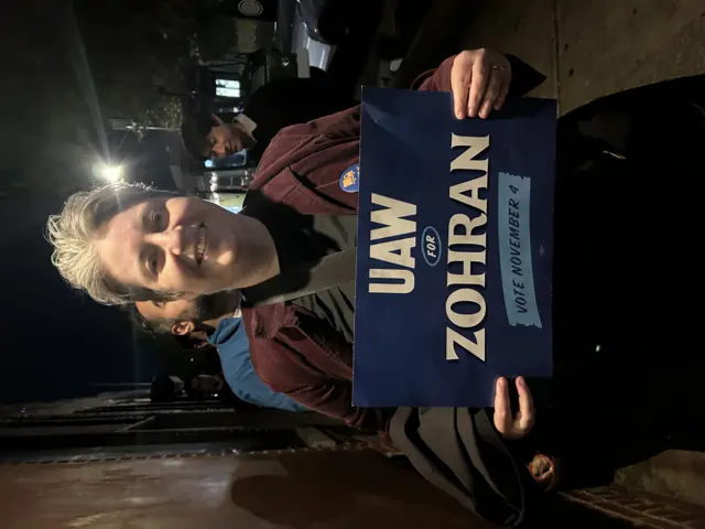 A person holding a Zohran sign